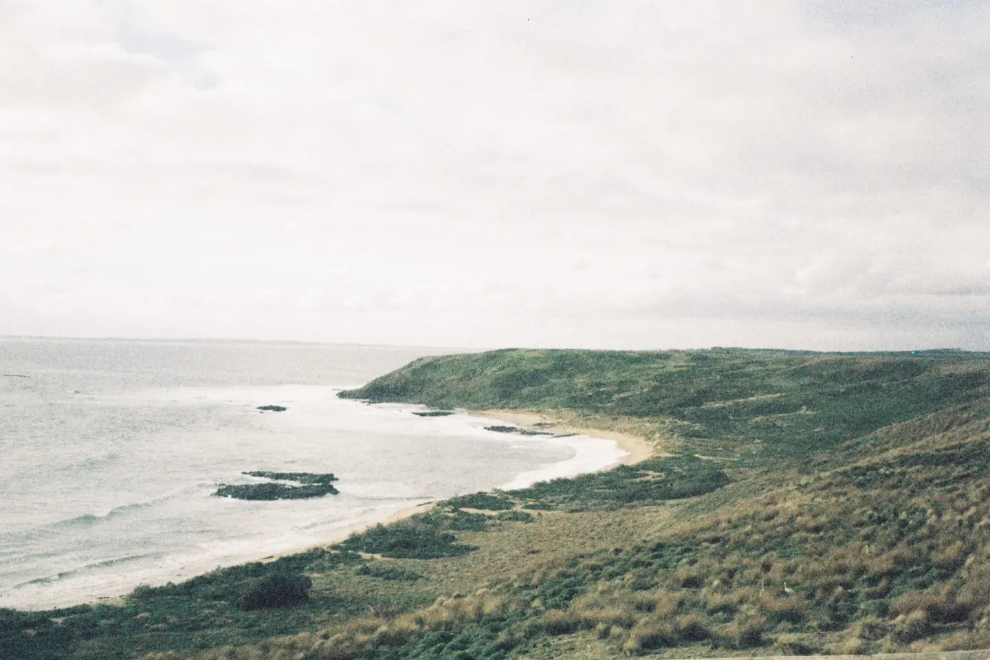 A sweeping coastal landscape with green hills and sea